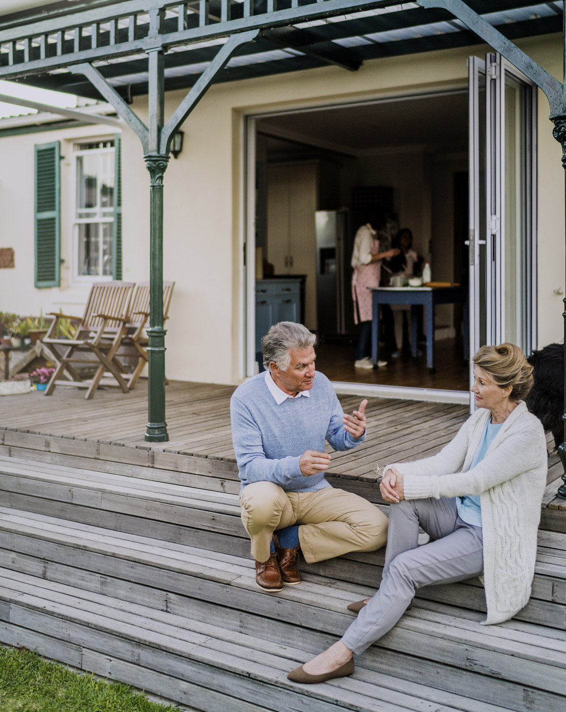 Retiree couple talking to each other while sitting on their front porch